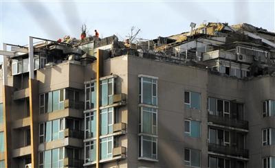 　　昨日，身穿橘黃色馬甲的工作人員在人濟山莊樓頂拆除違章建筑。新京報記者 吳江 攝