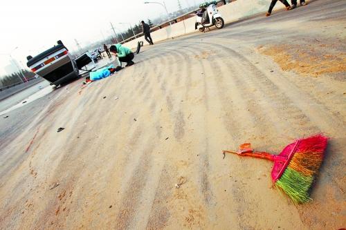 被撞的環(huán)衛(wèi)工躺在地上，身上蓋著藍(lán)色布塊，現(xiàn)場除散落的汽車碎片外，還留有被撞斷的掃帚。