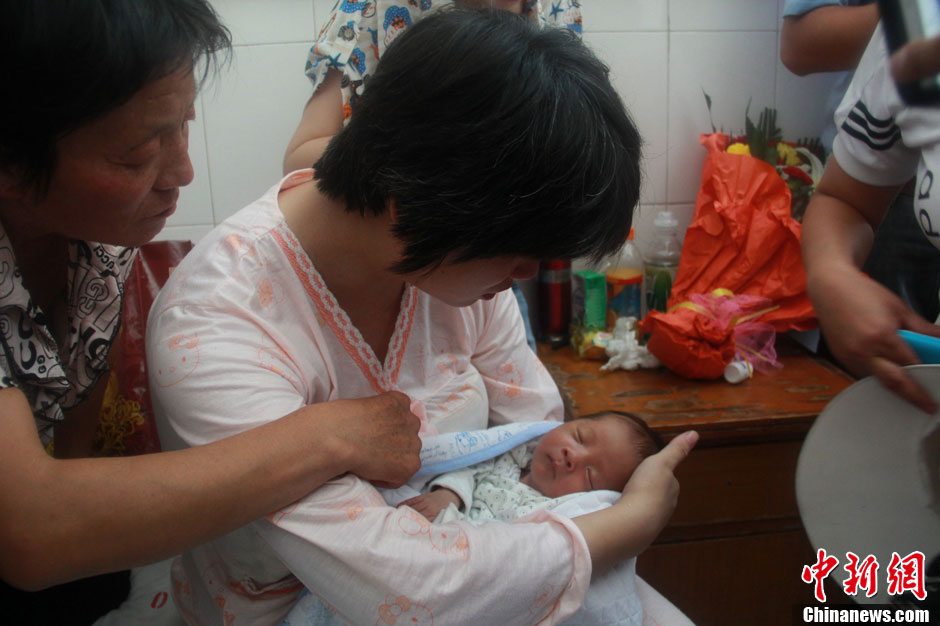 圖為久別重逢，獲救嬰兒母親悉心撫摸愛子。張一辰 攝