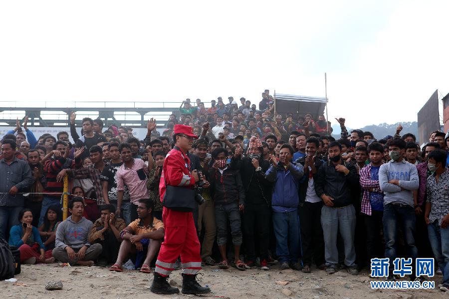 圍觀的尼泊爾民眾在中國國際救援隊成功搜救出幸存者后向搜救隊員歡呼致意。
