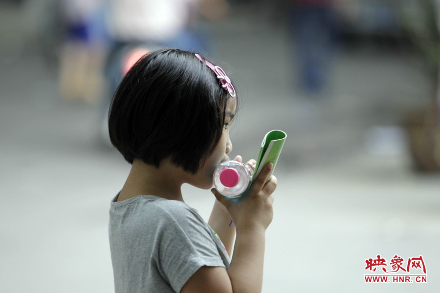 6月7日，鄭州回中考點(diǎn)，一名孩子拿著一瓶礦泉水，等待哥哥走出考場(chǎng)