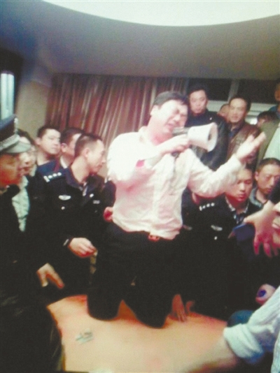 　4月19日，泰州市濱江工業(yè)園區(qū)管委會(huì)招待中心，一男子跪在酒桌上喊話求饒。李根 攝