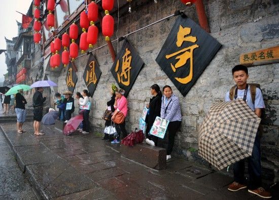 　4月29日上午11時20分，一些游客和古城當(dāng)?shù)氐木用穸阍谝粋€酒吧的屋檐下避雨。這些當(dāng)?shù)鼐用褚詾橛慰团恼罩\生，一場降雨讓他們的生意更加清淡。