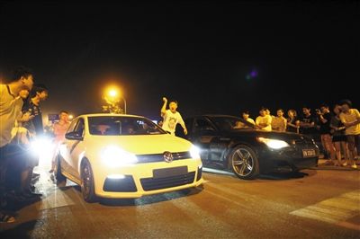 8月24日晚，東壩中街飆車現(xiàn)場，兩輛車并排等待出發(fā)指令，旁邊許多愛好者前來觀看比賽。新京報記者