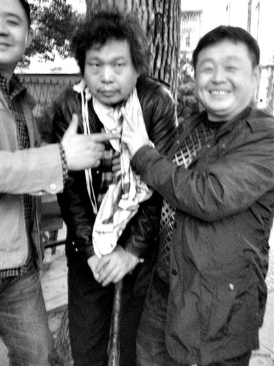 兩名接訪人員與患有癌癥的訪民段新德合影時，面帶笑容擺出勝利的手勢。