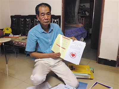 翻出一家網(wǎng)站贈予的“中國好人”證書，區(qū)少坤單膝跪在地上，“你看，我是中國好人啊?！?范春旭 攝