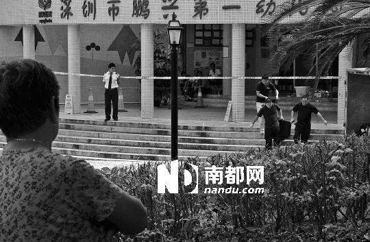 →7月19日，鵬興花園第一幼兒園門前，民警在現(xiàn)場(chǎng)進(jìn)行完勘查取證后，園長(zhǎng)和保安的尸體被運(yùn)走。南都記者 徐文閣 攝
