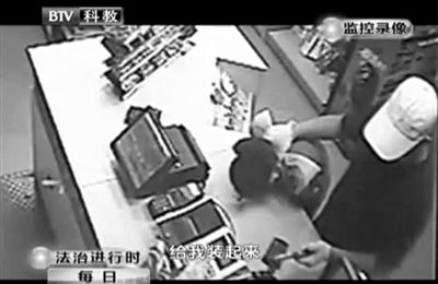 戴帽男子一手掐住加油站營業(yè)員，一手持發(fā)令槍指向另一營業(yè)員，要求“把錢給我裝起來”。