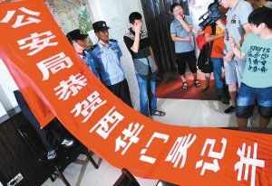 面對(duì)警方收繳的條幅，老板楊某也不好意思地用手遮擋臉