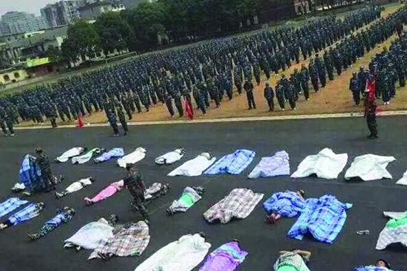 20多名女生躺在瀝青跑道上，身上嚴嚴實實地裹著棉被，接受太陽的照曬。