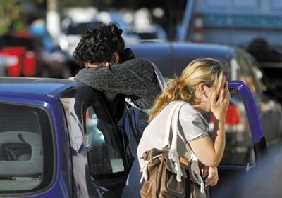 27日，遇難者親友在火災(zāi)現(xiàn)場(chǎng)旁哭泣。