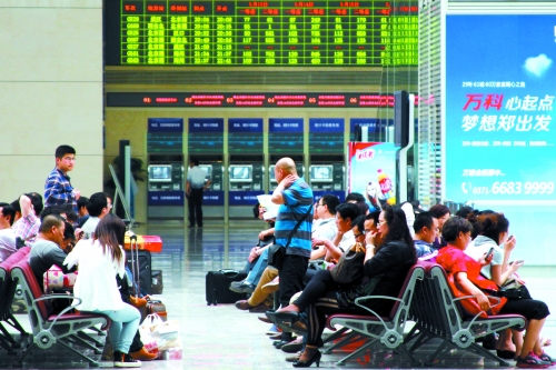 候車大廳溫度很高，一名乘客一手扇風、一手擦汗