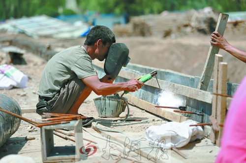 　正午陽光下，工地上的焊接工人還在認(rèn)真工作。
