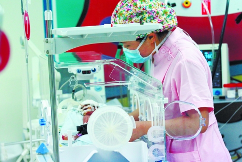 嬰兒在暖箱里受到醫(yī)護人員的精心照料