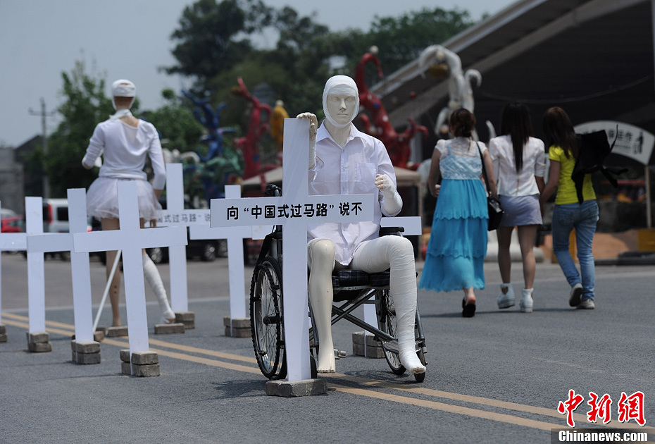4月16日，重慶市洋人街上擺放著兩個(gè)受了傷的塑料人像“模特”，旁邊十字架上寫著向“中國(guó)式過(guò)馬路”說(shuō)不
