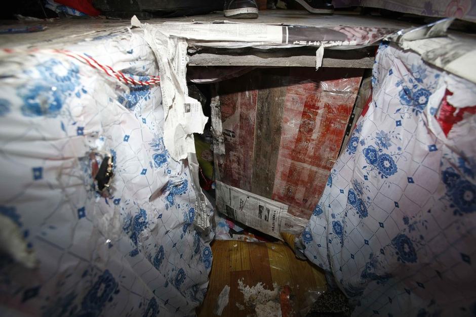 陳小龍?jiān)诔鲎馕萃?，自行又圍起一堵圍墻，安裝了一個門。圍墻上都是豎起的鐵釘，外面堆著土，鄰居猜是從地底挖出來的。洞口就在床邊，0.5米見方，深約1.5米。洞口表面一塊紙板掩蓋，打開紙板跳入洞底，是一扇小木門，木門外有插銷，可以從外面鎖上。