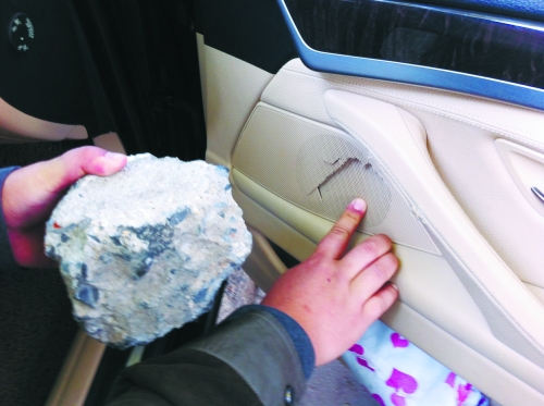 “飛”進(jìn)寶馬車內(nèi)的大石塊,將寶馬車的車門內(nèi)飾板砸爛。