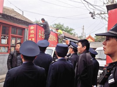 昨日下午,東城區(qū)工商、城管、公安等部門,對雍和宮附近的預測中心進行清理整頓,站在車頂?shù)膬擅と苏鸪患摇邦A測中心”的招牌。因雍和宮、白云觀等文化景點外聚集大量算命先生,被媒體稱為“算命一條街”。本版攝影/新京報記者 李寧 攝