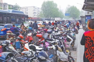 省人民醫(yī)院北門，路邊的公交站牌處停滿非機動車，上、下客只能在快車道上。