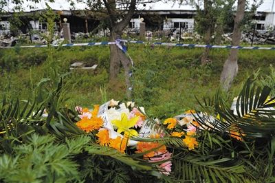 昨日，吉林省德惠市吉林寶源豐禽業(yè)有限公司燃燒事故現(xiàn)場警戒線外，遇難者家屬在路邊擺放了花圈祭奠逝去的親人。吳江 攝