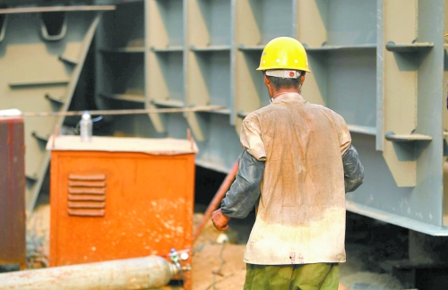 工地上，一建筑工人的衣服被汗水浸透。