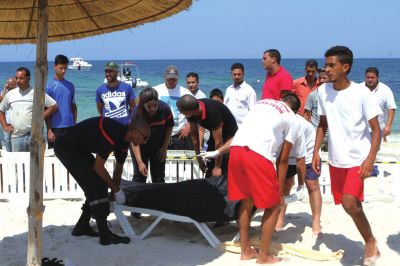 6月26日，在突尼斯蘇塞，救生員和醫(yī)務(wù)人員在發(fā)生襲擊事件的海灘運送一名死者的遺體。新華社發(fā)