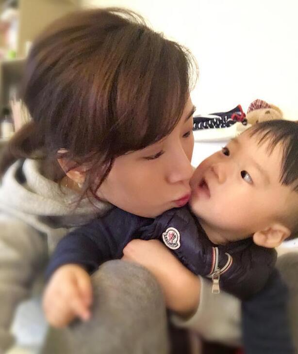 照片中李念狂吻兒子，小寶貝自顧自地玩著。