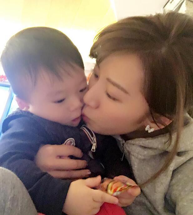 照片中李念狂吻兒子，小寶貝自顧自地玩著。