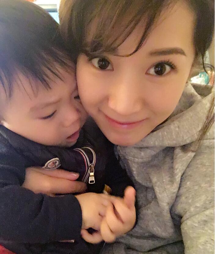 照片中李念狂吻兒子，小寶貝自顧自地玩著。