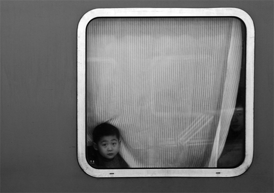 一個(gè)孩子把頭伸向窗外，他想再看送別的親人一眼