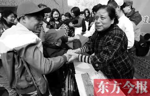 昨日，鄭大四附院的大樓前，“面人鄭”鄭玉芬（右）向前來捐款的殘疾人表示感謝