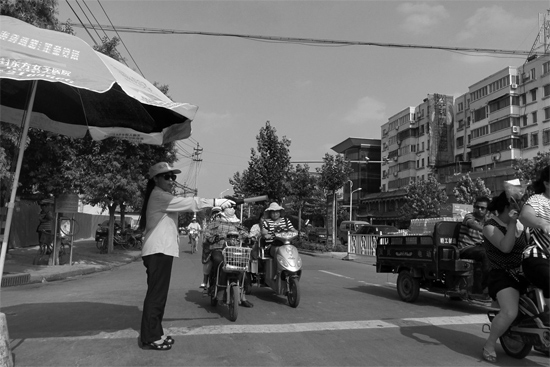昨日，開封市區(qū)一名協(xié)管員在指揮群眾過馬路