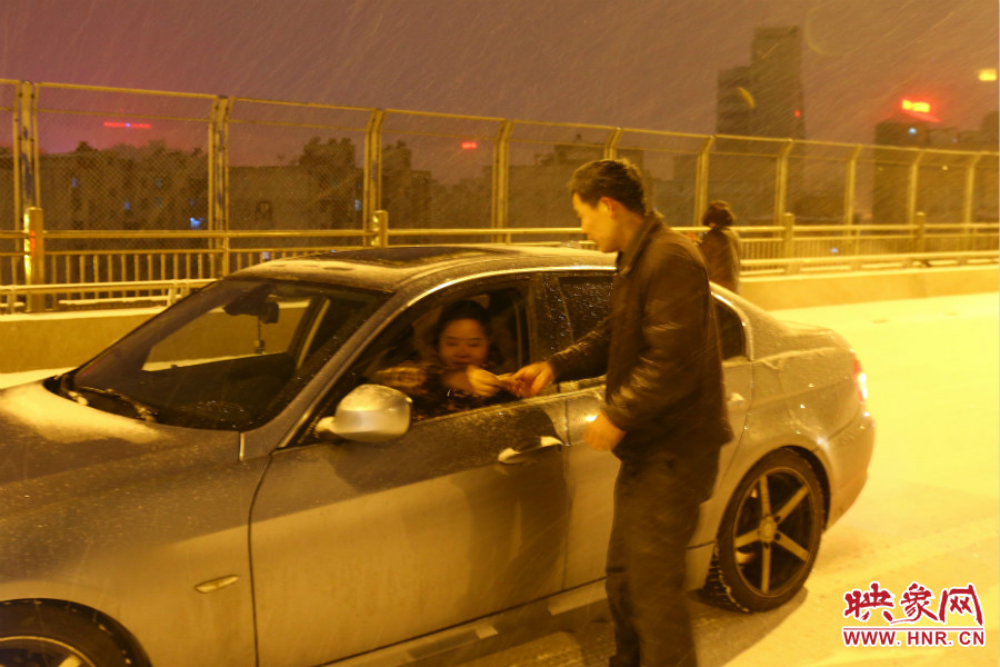 “推車人”幫助一輛車上坡后，收取“勞務(wù)費”。