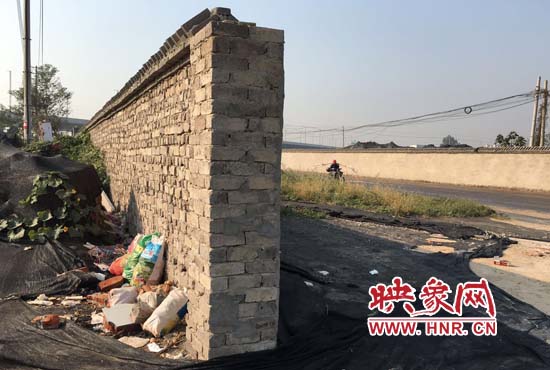 一墻之隔，一邊是道路，一邊是垃圾和荒草，市民質(zhì)疑其為遮羞墻。