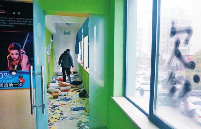 　健身會(huì)所地上一片狼藉，玻璃上噴著黑色“欠錢”二字。