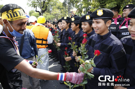 2013年12月03日,曼谷總理府與曼谷警署允許反政府示威民眾進(jìn)入,雙方進(jìn)入暫時“停戰(zhàn)”狀態(tài)迎接泰王生日。曼谷警察總署,女警們手持鮮花送給反政府示威民眾。圖片來源:Manish Swarup/東方IC
