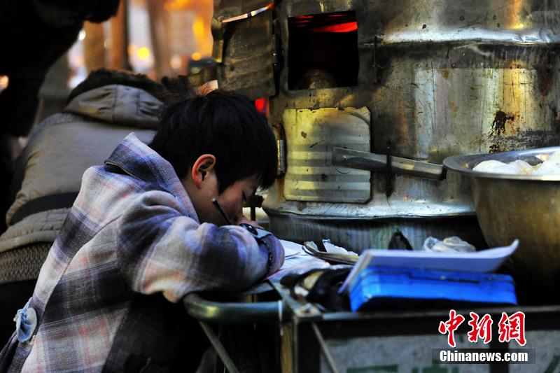 男孩西安路燈下寫(xiě)作業(yè) 媽媽邊賣紅薯邊輔導(dǎo)