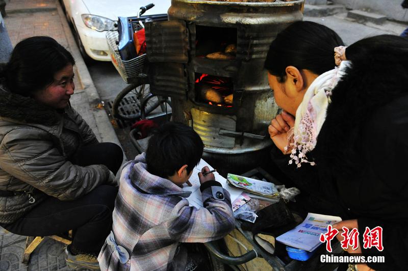 男孩西安路燈下寫(xiě)作業(yè) 媽媽邊賣紅薯邊輔導(dǎo)