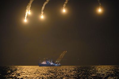 22日，搜救人員在照明彈的光亮下連夜搜救。