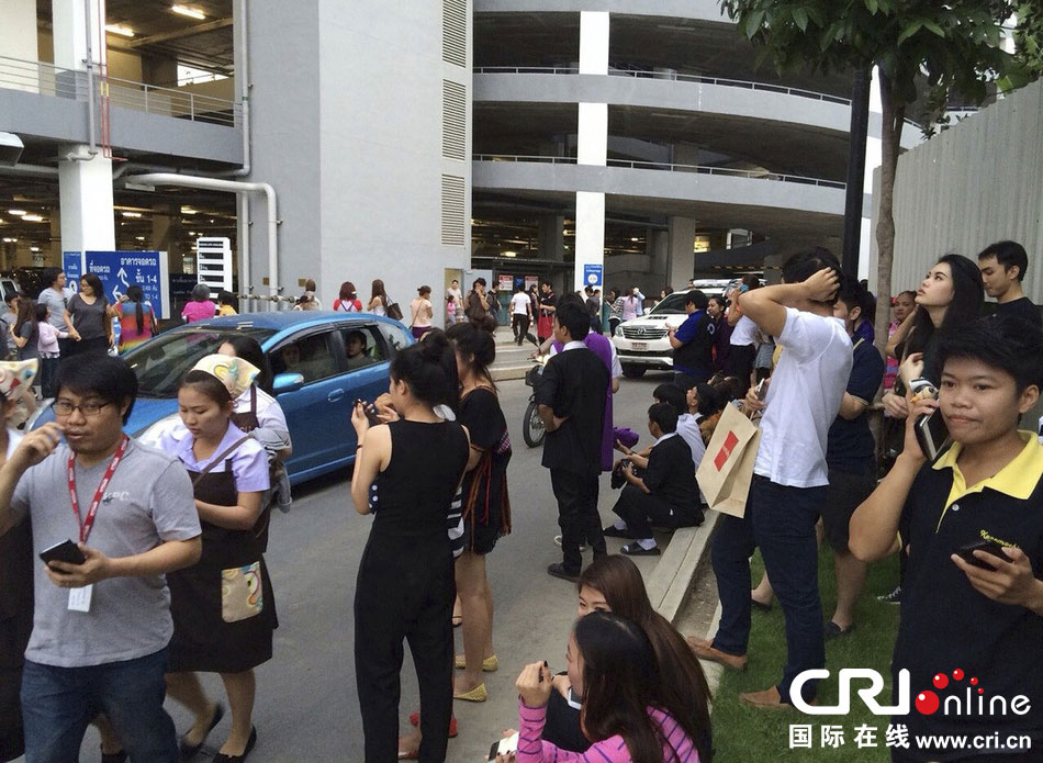 當?shù)貢r間2014年5月5日，泰國清萊，工人們站在一棟大樓外避難。