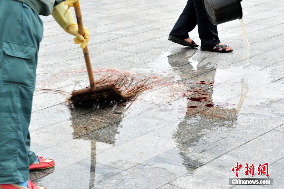 圖為環(huán)衛(wèi)工人在清理案發(fā)地點(diǎn)的血跡。