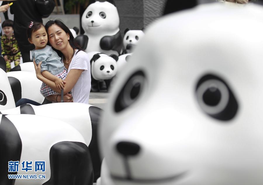 6月2日，一位家長(zhǎng)帶著孩子在上海街頭和大熊貓模型合影。