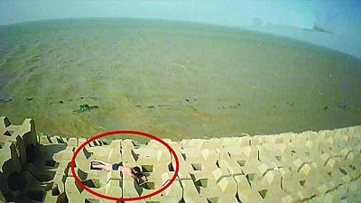 孫正龍游上岸，趴在海邊精疲力盡。