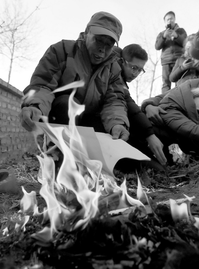 李三仁在兒子墳前焚燒再審無罪判決文書的復(fù)印件。新華社發(fā)