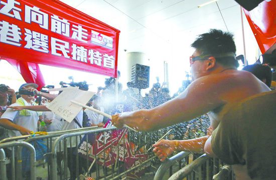 17日，在香港立法會(huì)外，一名反對(duì)政改的男子向支持派人群投擲標(biāo)牌。