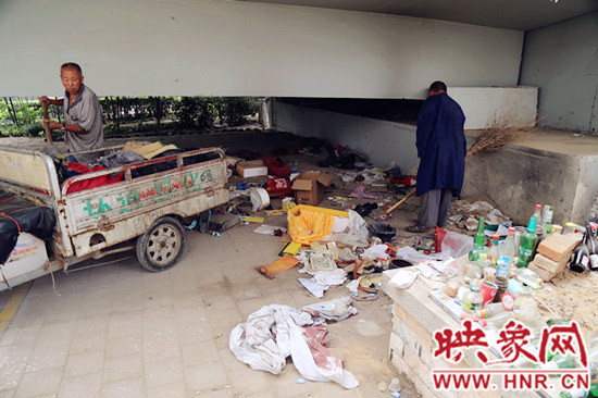 負(fù)責(zé)高架橋下綠化的人員在清理流浪漢留下的垃圾和雜物。