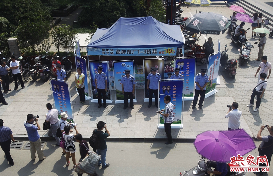 執(zhí)法人員用宣傳牌圍擋占道經(jīng)營(yíng)攤位。