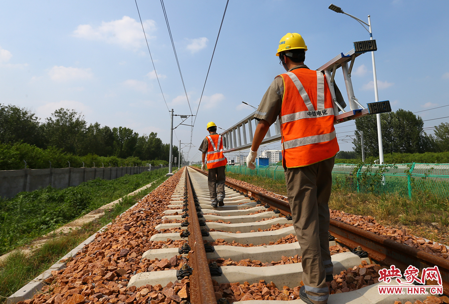 滾燙的鐵軌上，兩個(gè)扛著梯子的檢修員走向第四個(gè)檢修點(diǎn)