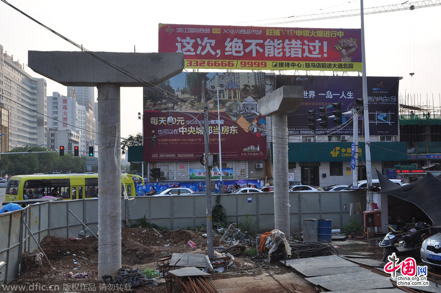 過街天橋一側(cè)的橋樁早已打好,可是對(duì)面的郵政銀行網(wǎng)點(diǎn)依舊在照常營業(yè)。