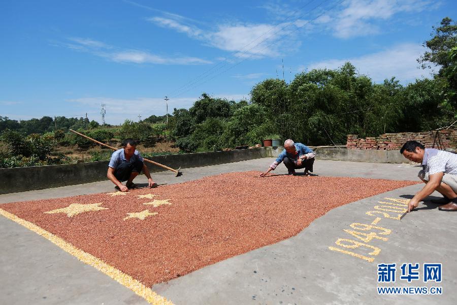 村民馬玉明（左一）用豐收的高粱和玉米在院壩里擺國(guó)旗為祖國(guó)慶生。